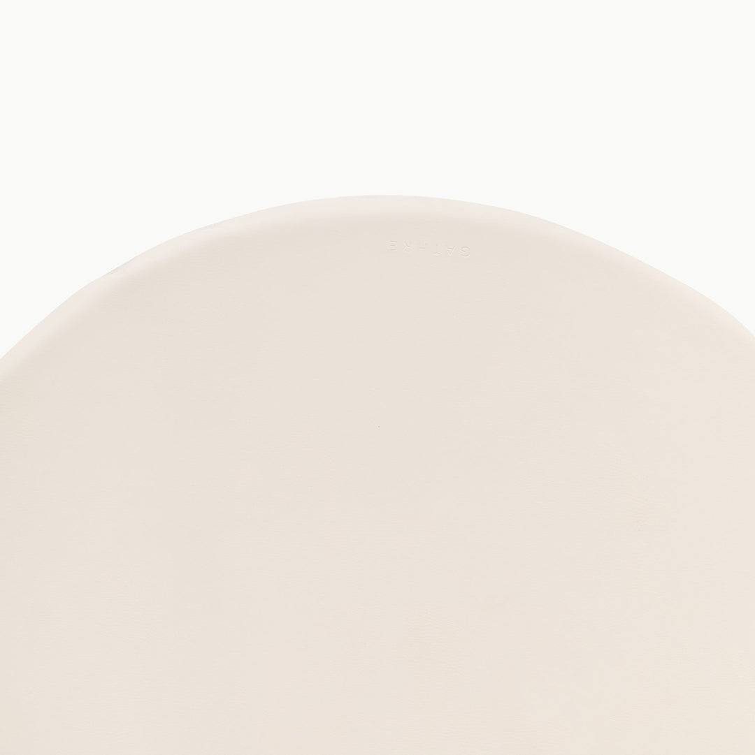 Cream round padded play mat, close-up of the wipeable vegan leather surface.