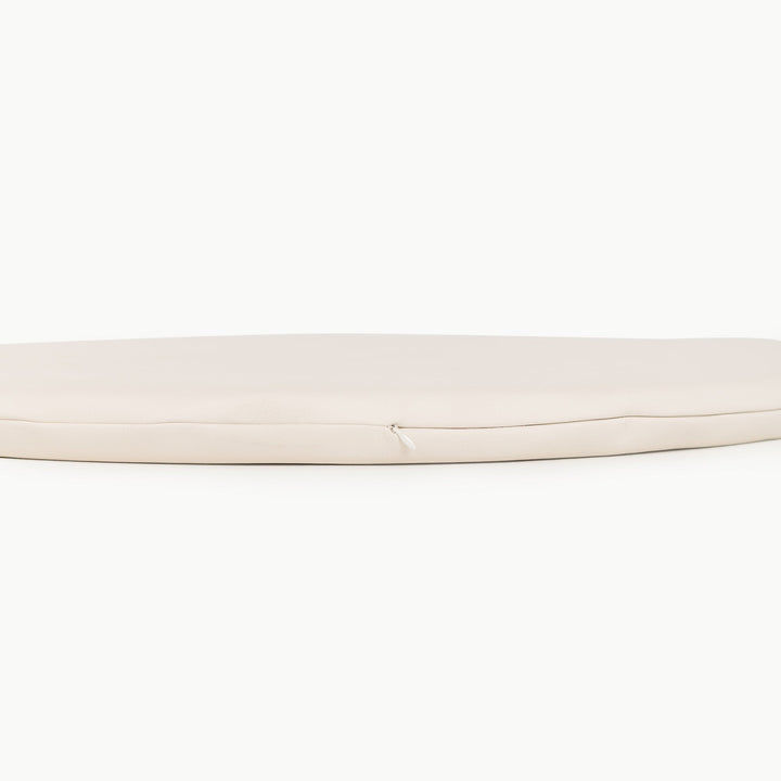 Cream round padded play mat side view showing the cushioned zippered edge.