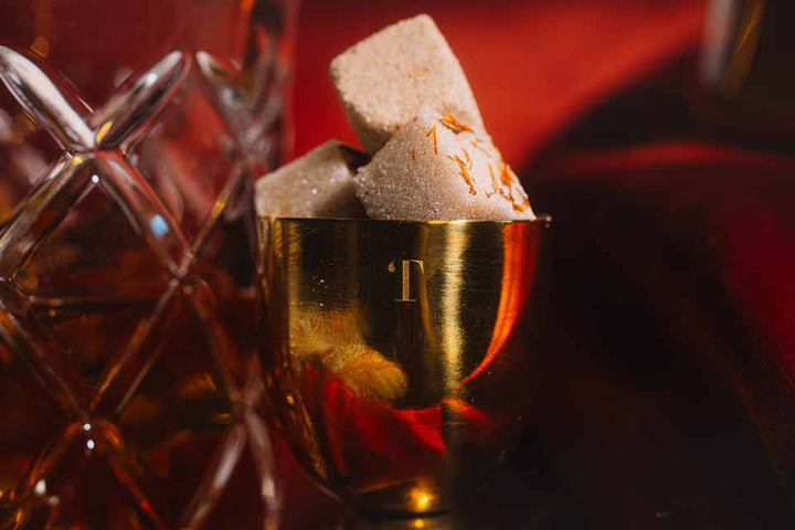 Jigger of bourbon beside holiday old fashioned mixer cubes