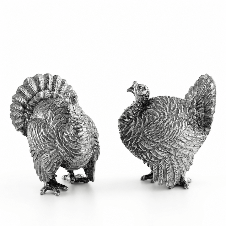 Pair of pewter turkey salt and pepper shakers with fanned tail feathers on a white background