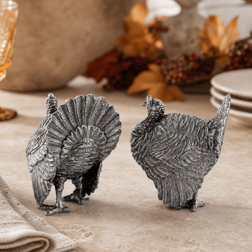 Pewter turkey shakers on a harvest tablescape with dried autumn leaves and berries