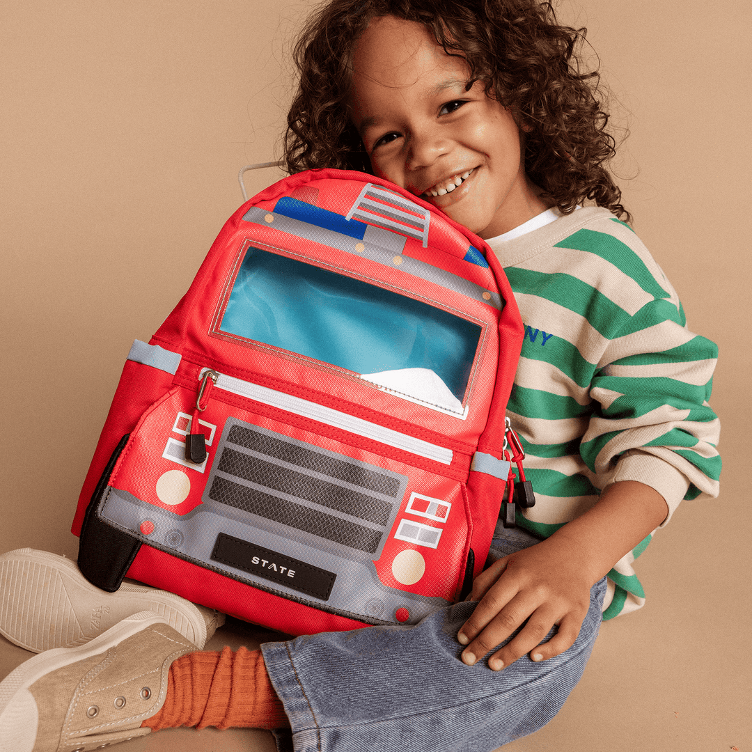 Smiling child hugging the fire truck backpack