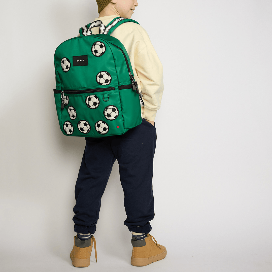 Boy seen from behind wearing the green Fuzzy Soccer Balls STATE Kane backpack