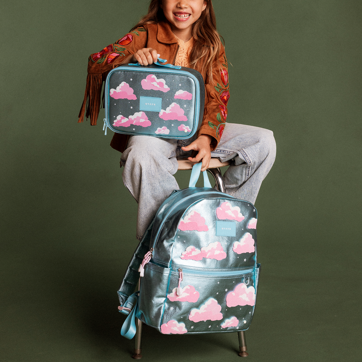 Girl seated with the Clouds backpack and matching Clouds lunch box