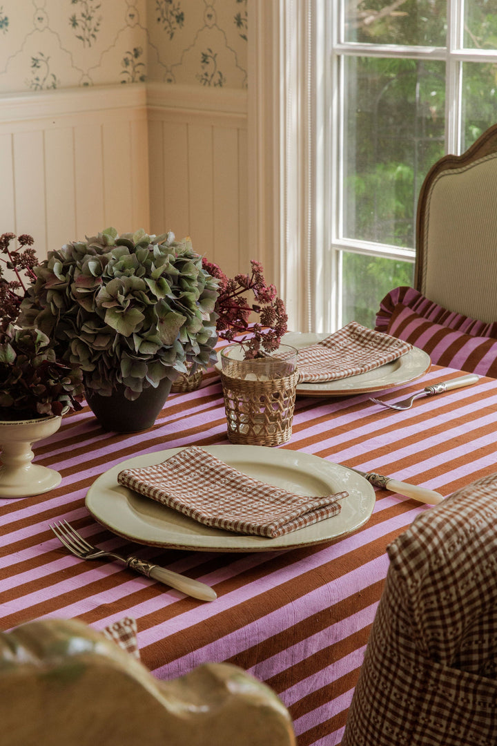 Lilac and brown stripe tablecloth on a dining table set for a fall dinner by a window