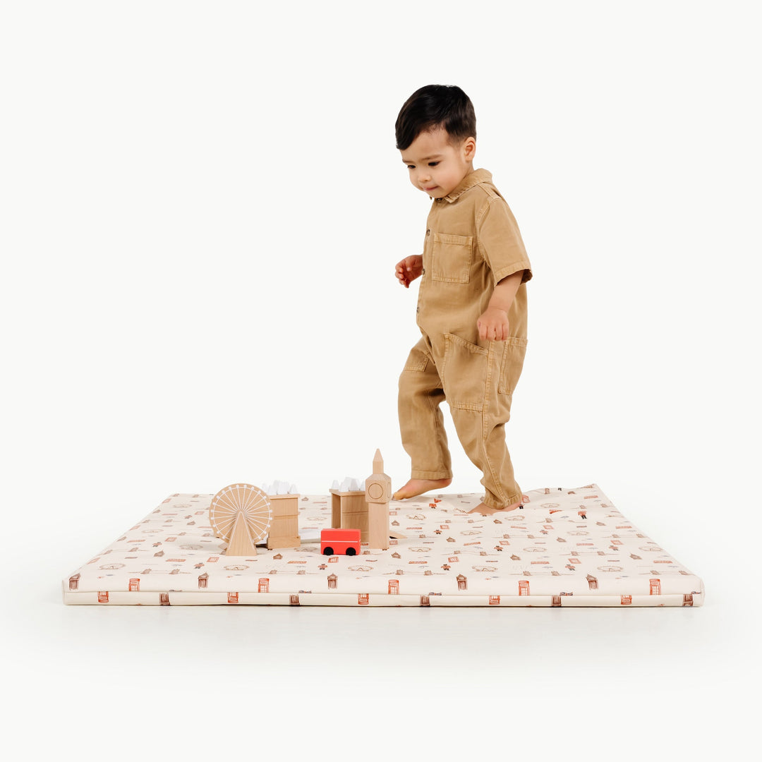 Toddler walking on the square London print padded play mat with wooden London landmark toys
