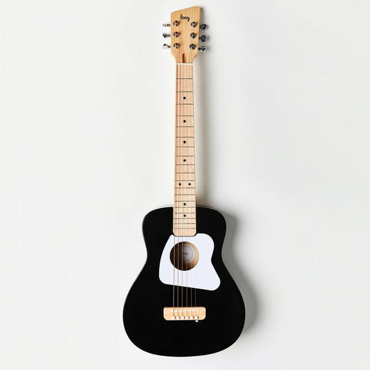Black acoustic guitar with a white soundhole on a light gray background