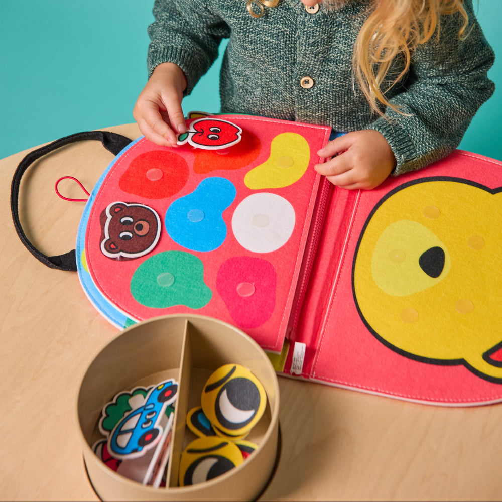 Child playing with the opened felt Montessori kit and a bin of felt shape pieces