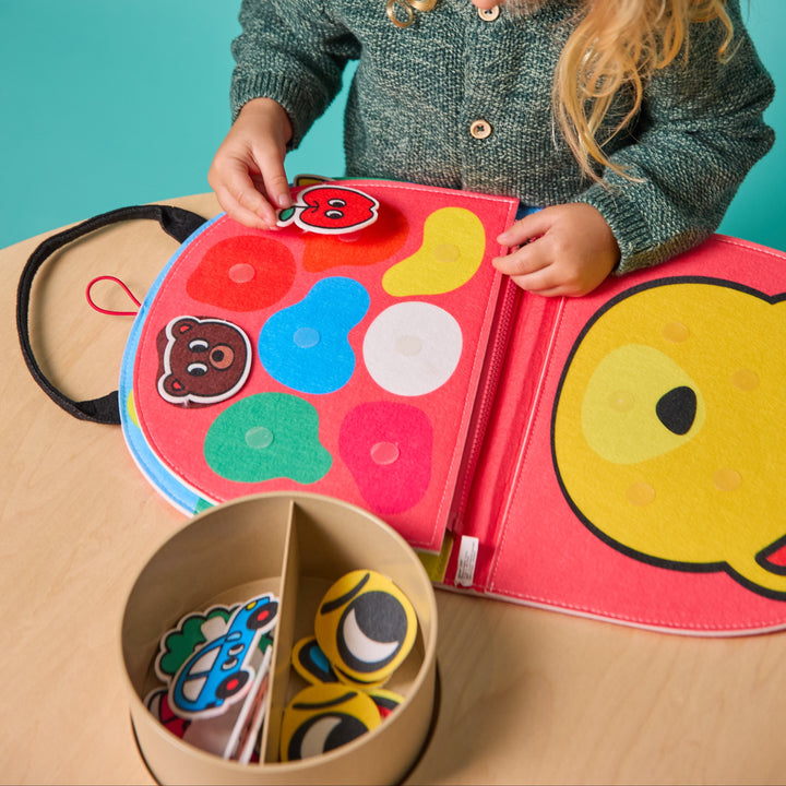 Child playing with the opened felt Montessori kit and a bin of felt shape pieces