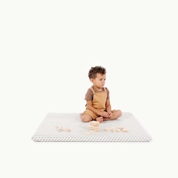 Blue floral block-print square padded play mat with a toddler sitting and playing.