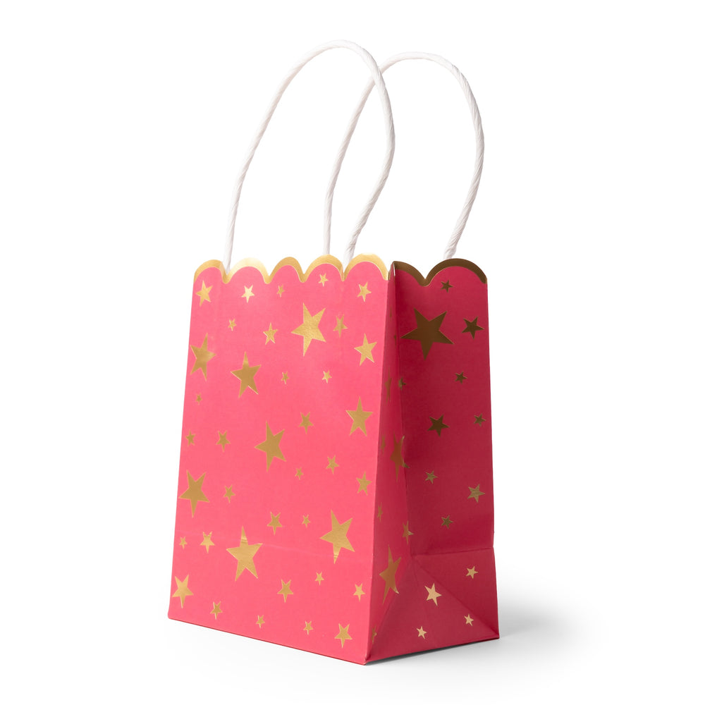 A pink party favor bag with gold foil star patterns and white twisted paper handles, shown on a clean white background.