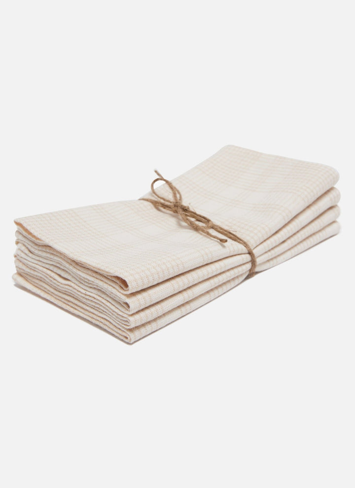Stack of four cream plaid cotton napkins tied with twine on a white background