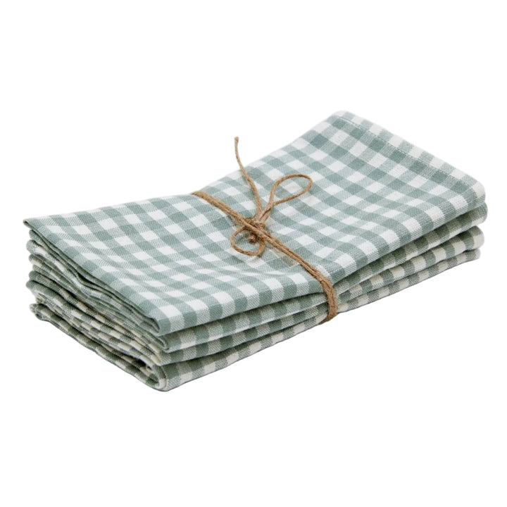 A stack of folded green and white gingham check linen napkins tied with a natural jute twine bow, set against a plain light gray background.