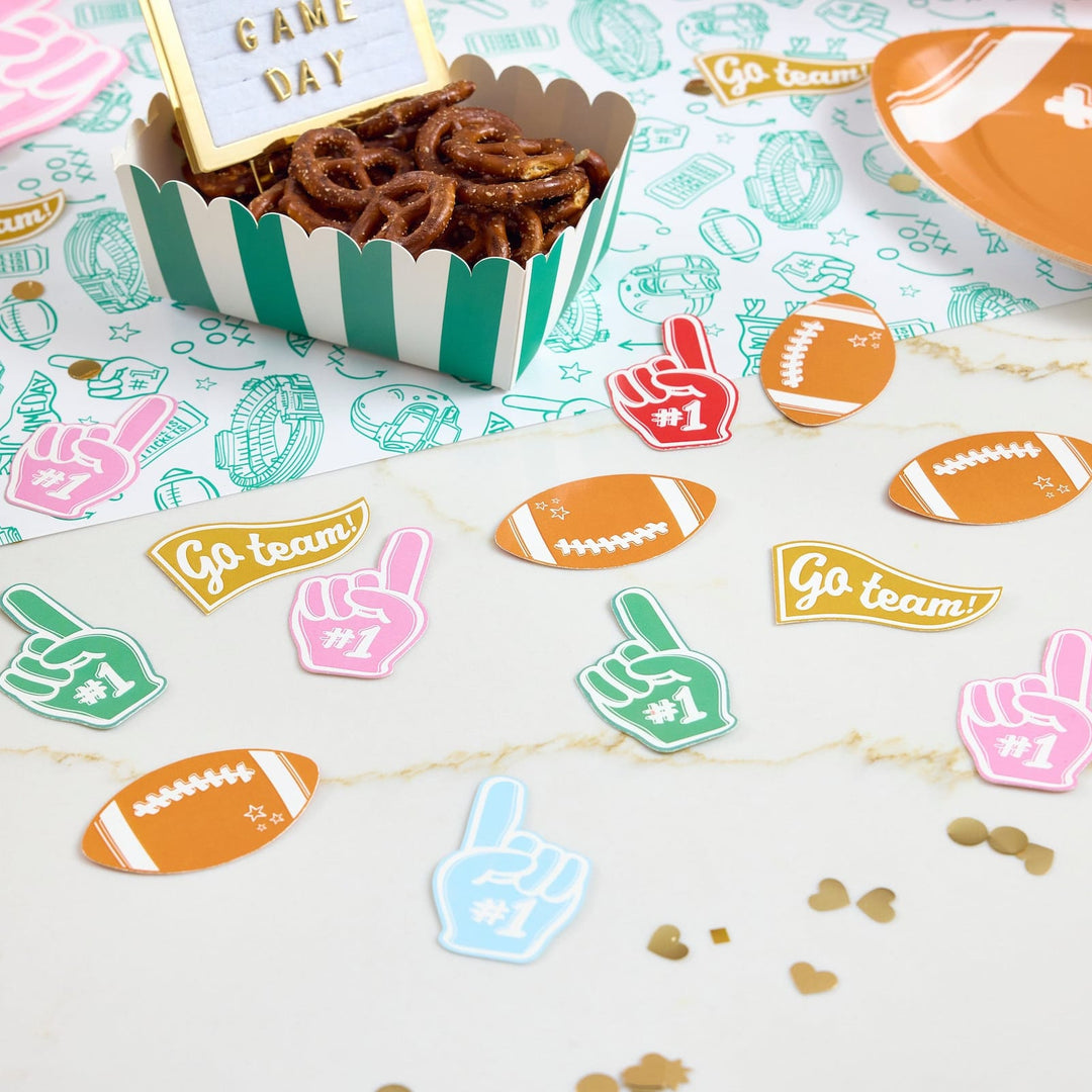 Game day table with jumbo football confetti, a Game Day sign, and a pretzel box