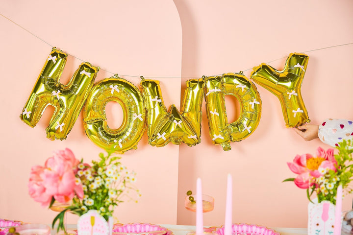 Howdy Darling balloon banner in gold letters with pink satin bows