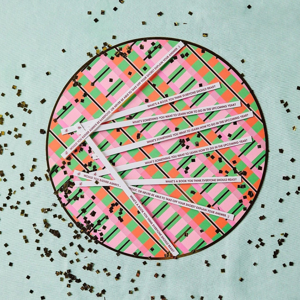Printed conversation sticks fanned across a plaid round tray with gold confetti