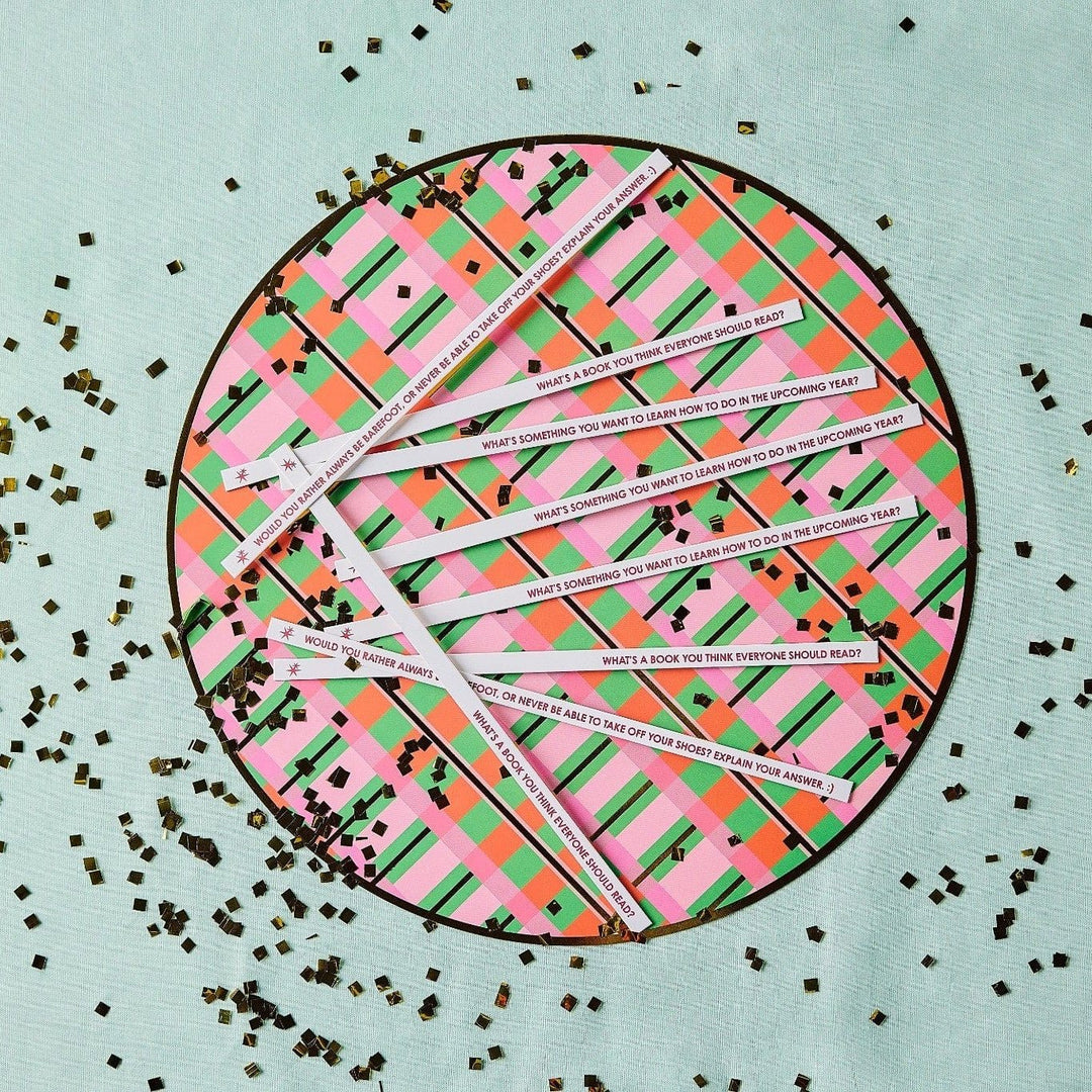 Printed conversation sticks fanned across a plaid round tray with gold confetti