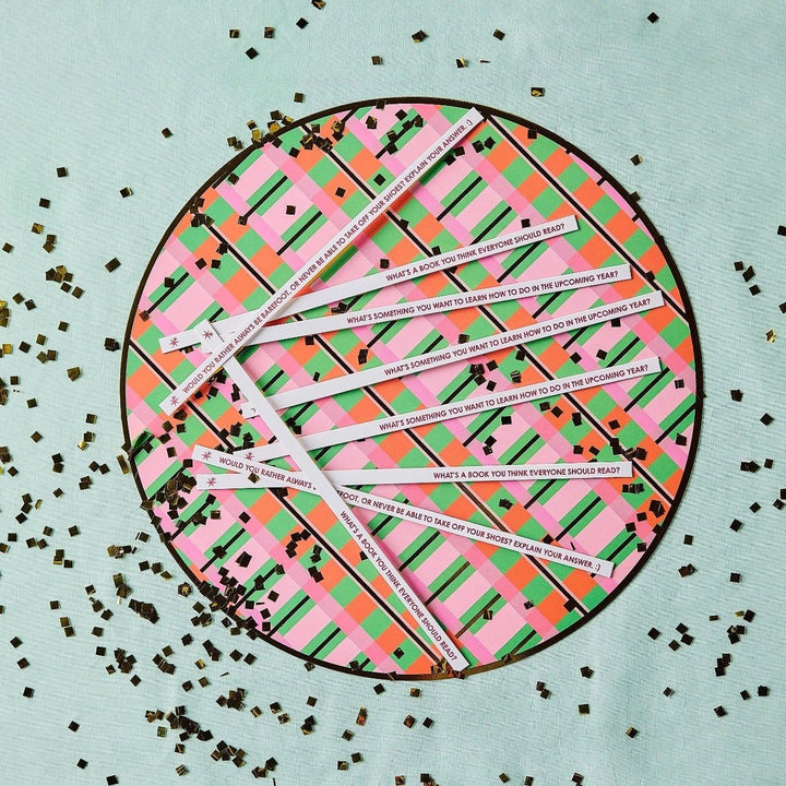 Printed conversation sticks fanned across a plaid round tray with gold confetti