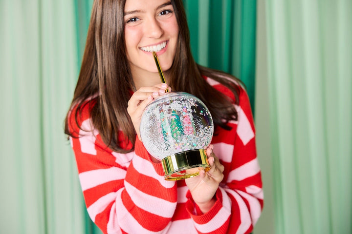 Holiday snow globe sipper cup with a gold base and reusable gold straw for Christmas hot cocoa