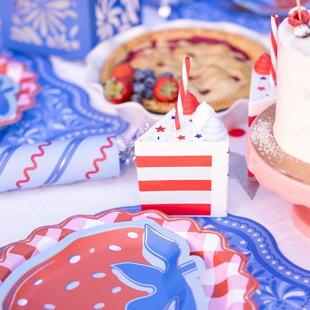 Patriotic cake slice cup beside a berry pie and strawberry plates on a blue and white table