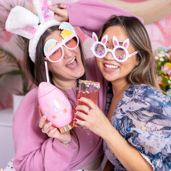 Two friends in bunny ears and bunny glasses posing with the pink Easter egg cup