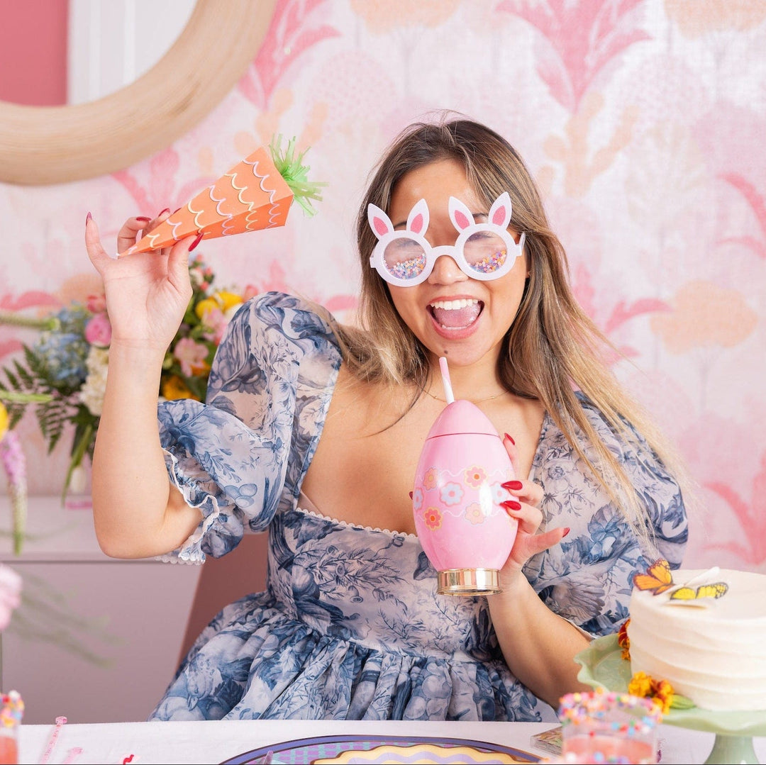 Woman in bunny glasses sipping from the pink Easter egg cup at a spring party table