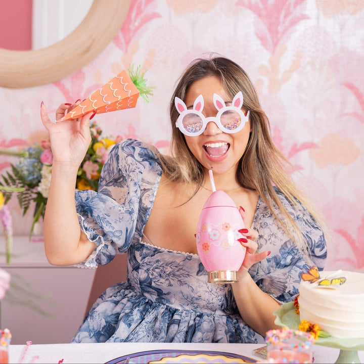 Woman in bunny glasses sipping from the pink Easter egg cup at a spring party table