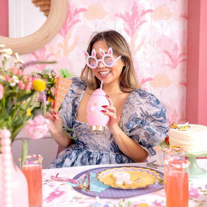 Woman at an Easter brunch table holding the pink egg sipper to her face