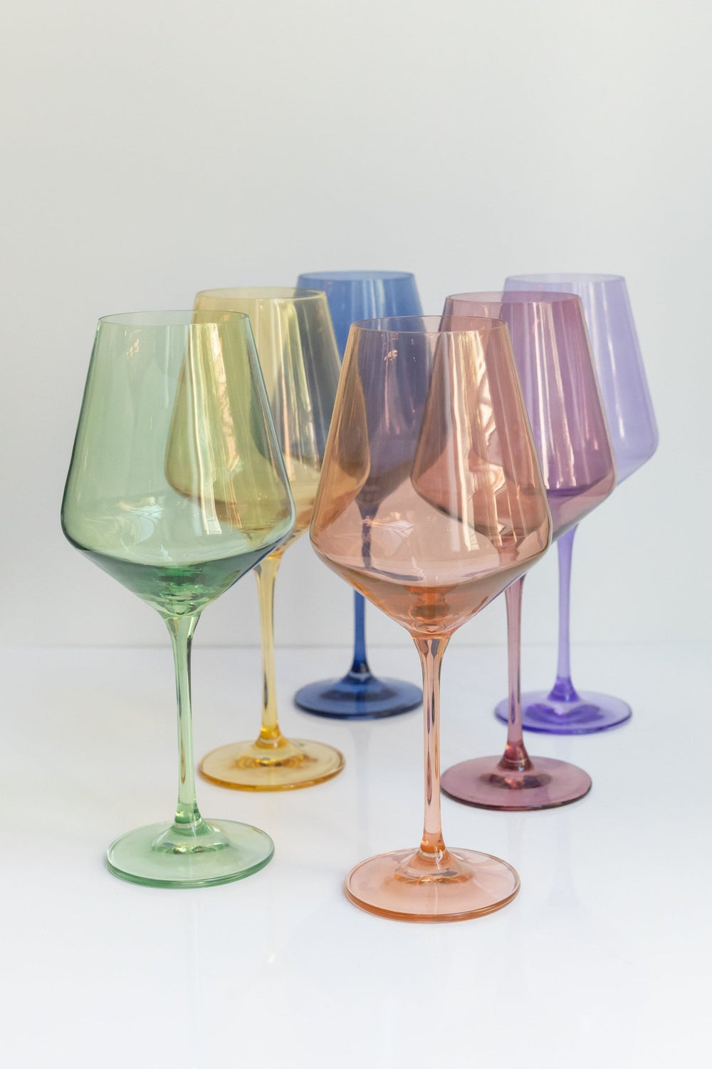 Estelle mixed pastel colored glass wine glasses grouped on a pale grey backdrop, for a celebration table