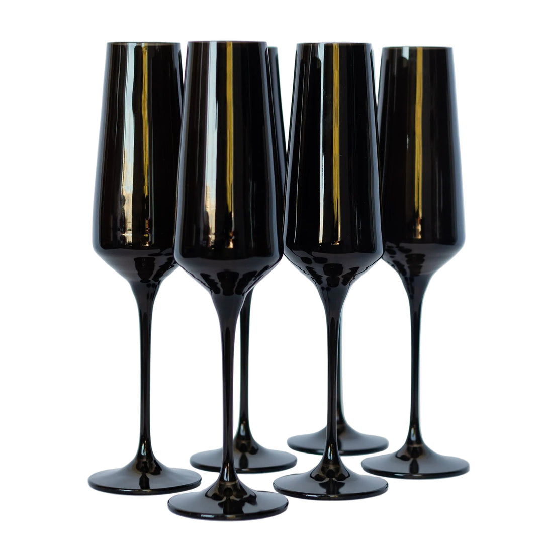 Four black champagne flutes with gold accents on a light gray background