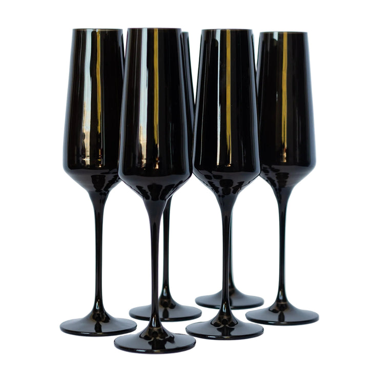 Four black champagne flutes with gold accents on a light gray background