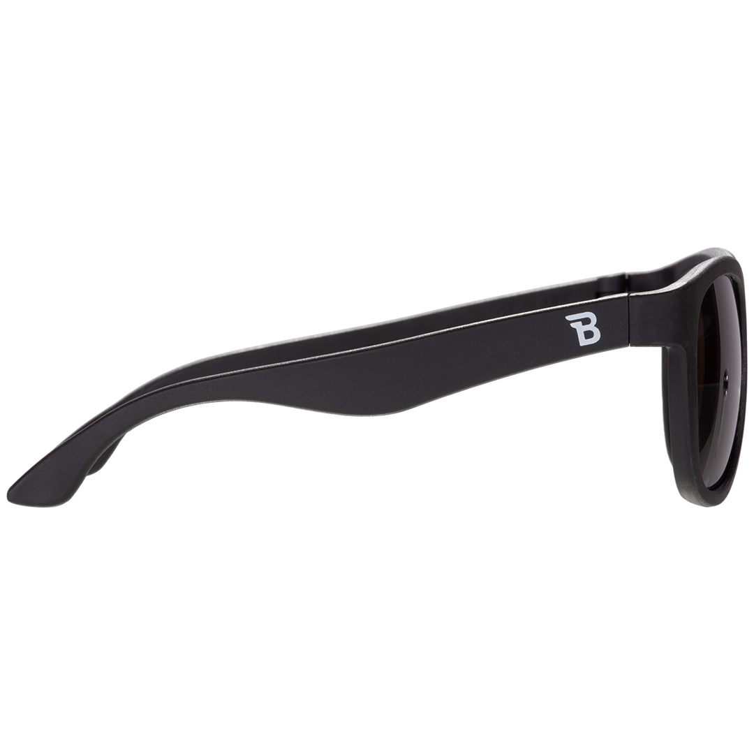 Side profile of black aviator kids sunglasses showing the flexible temple arm and Babiators logo.