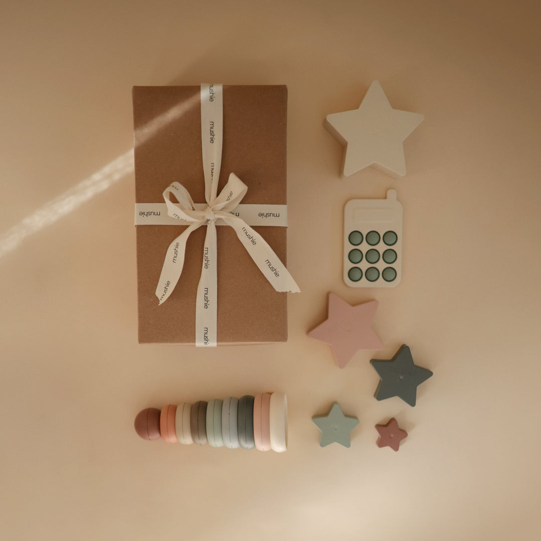 Baby with toys from the Mushie everyday play gift set