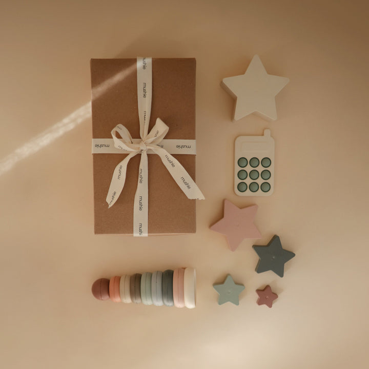 Baby with toys from the Mushie everyday play gift set