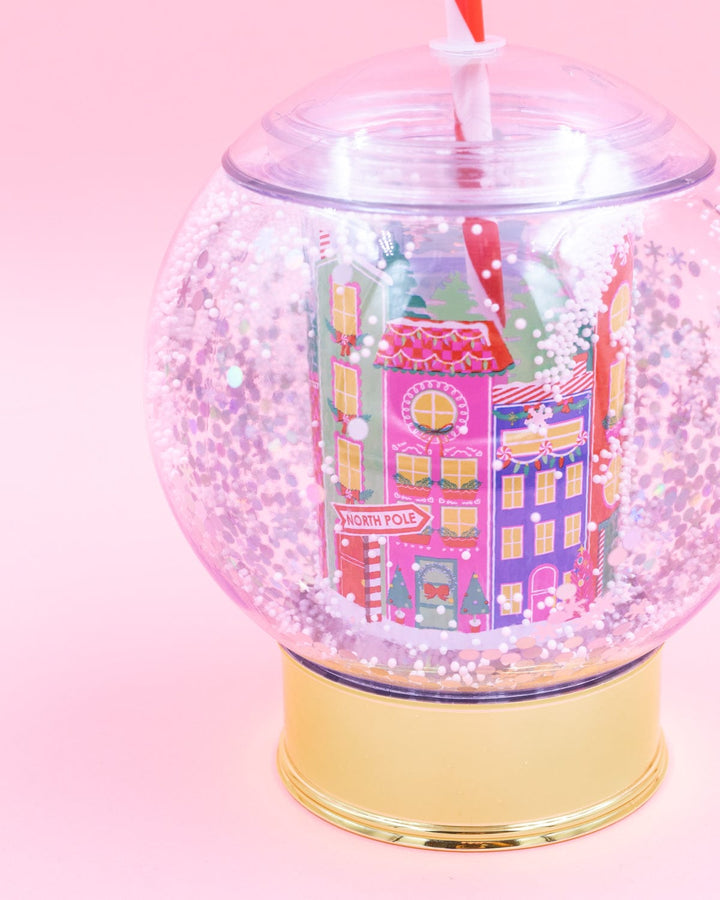Close-up of the snow globe cup showing the pink and purple village buildings and floating snow
