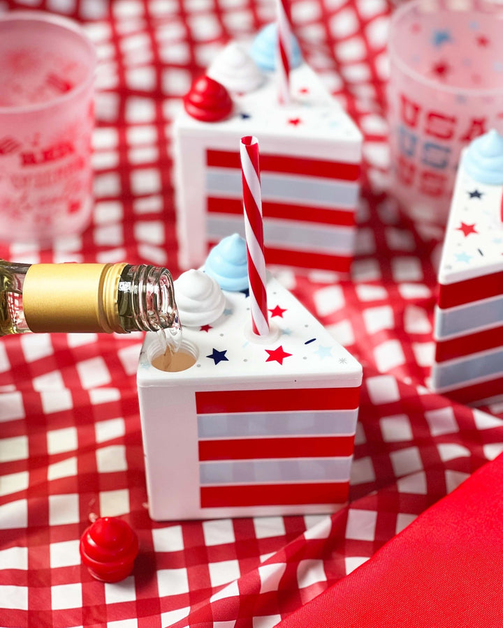 Champagne poured into a patriotic cake slice cup on a red gingham tablecloth