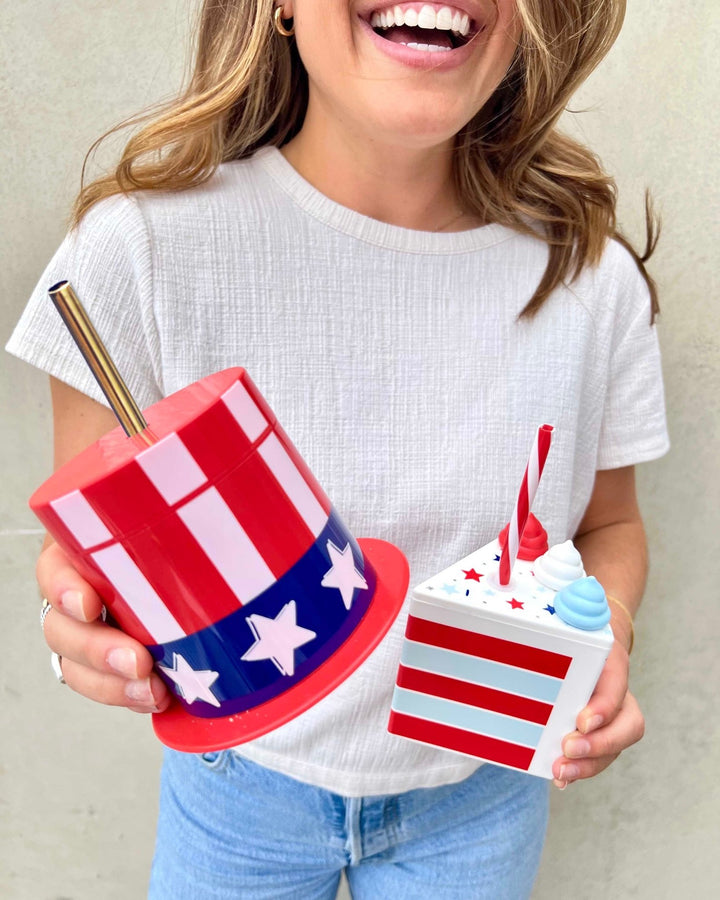 Woman laughing and holding a patriotic cake slice cup and a striped top hat sipper