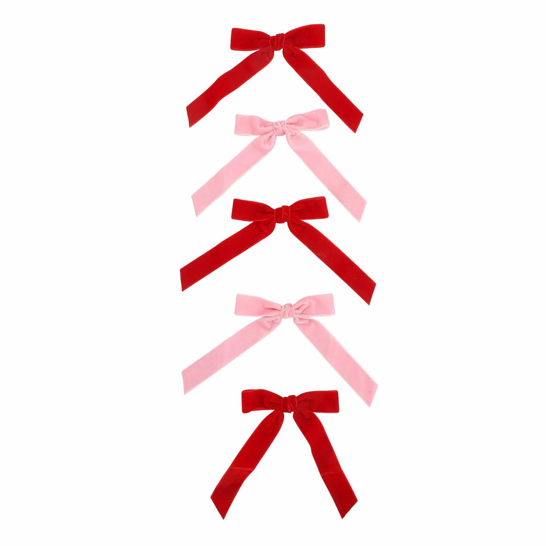 Five red and pink velvet bows arranged in a column on a white background