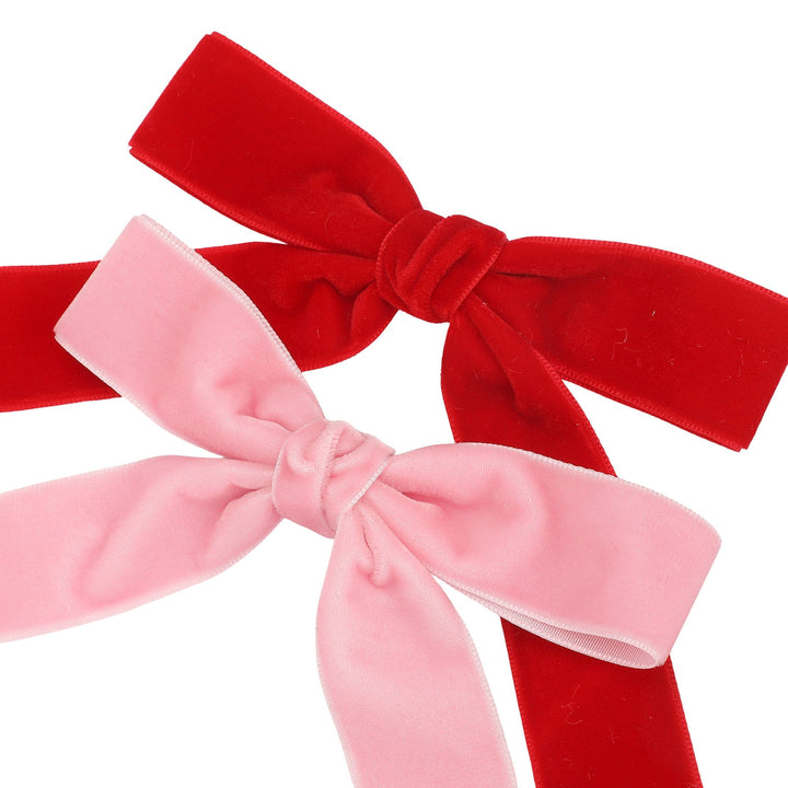 Pink and red velvet bows with long tails on a white background