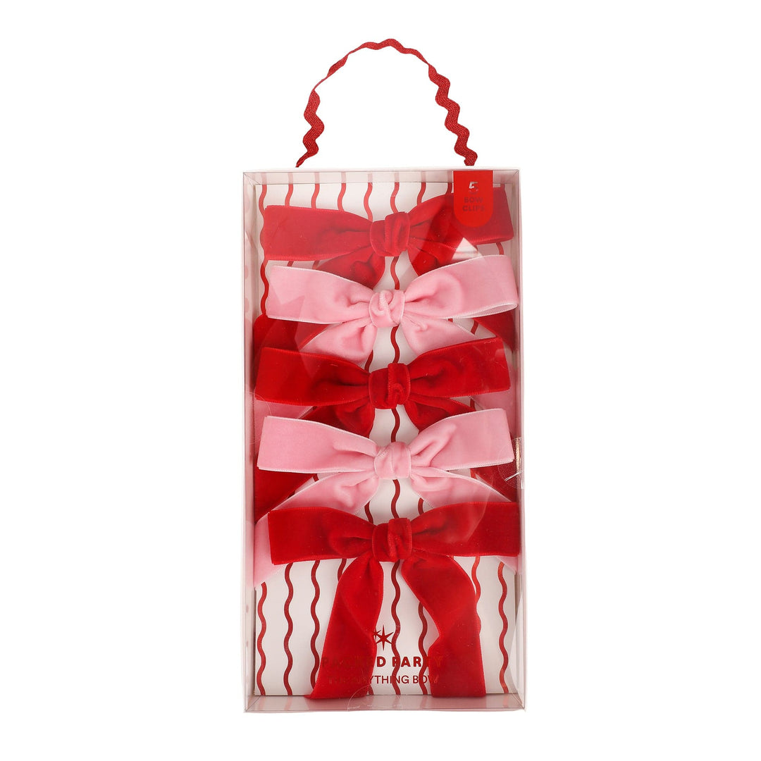 Five pink and red velvet clip-on bows in a clear pouch with a rickrack hanger