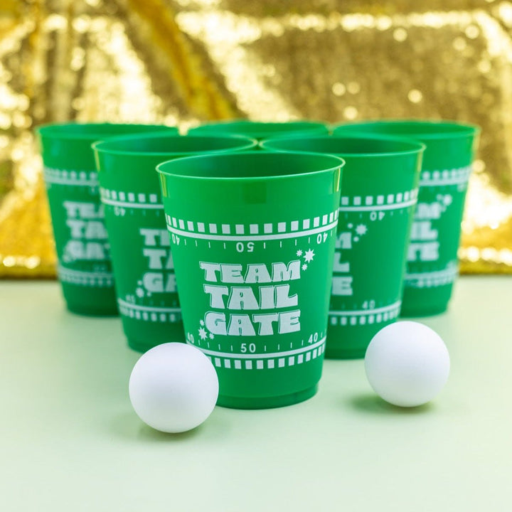 Six green Team Tailgate cups racked in a triangle with two ping pong balls