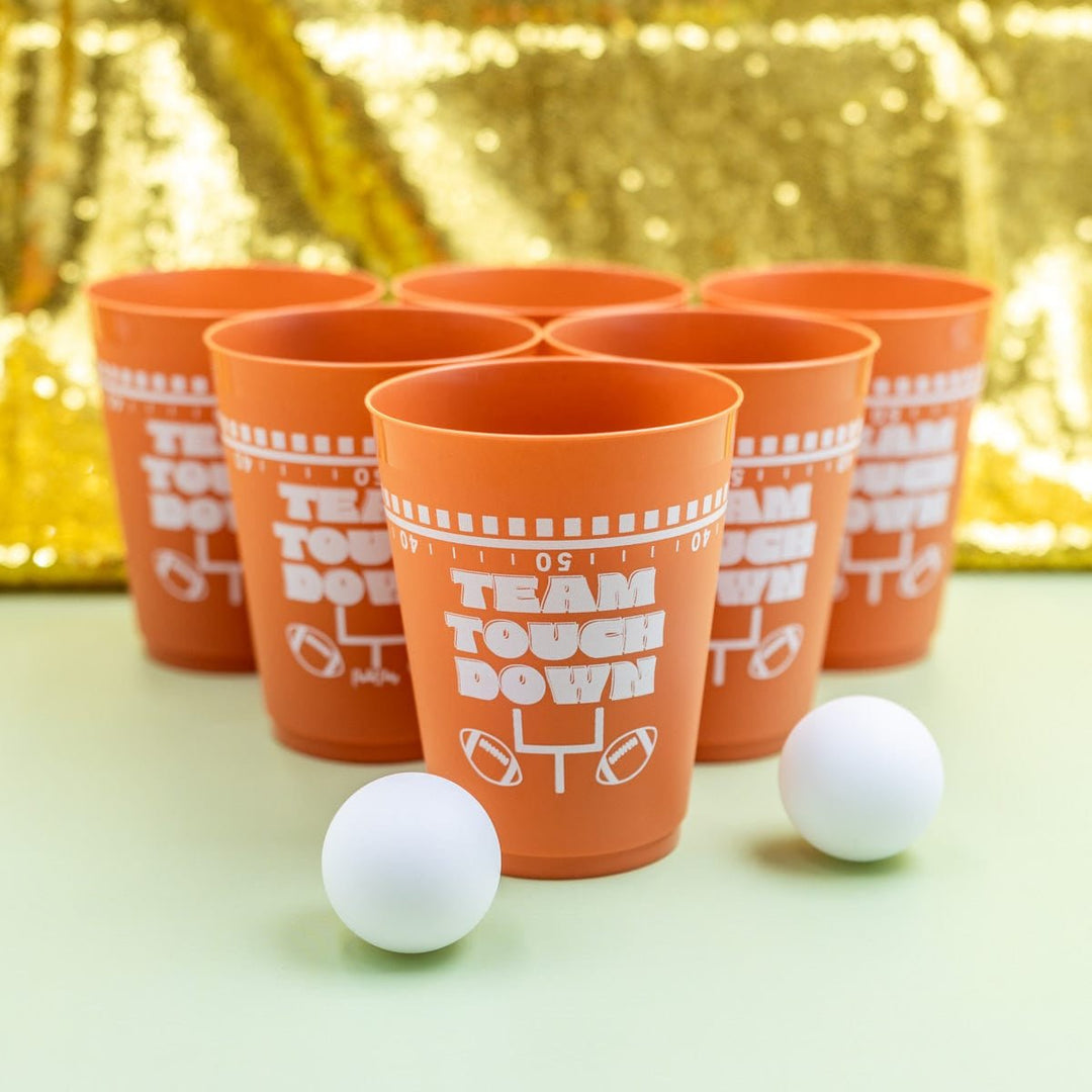 Six brown Team Touchdown cups racked in a triangle with two ping pong balls
