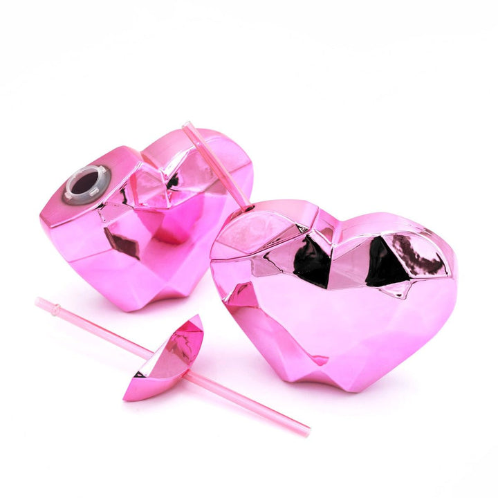 Two faceted pink heart sipper cups with pink stopper straws on a white background