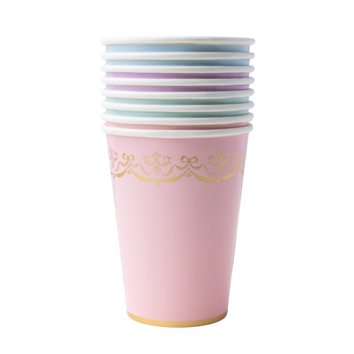 A stack of pastel party cups on a white background, featuring a light pink cup in the front with a gold decorative border and a gold base, with other cups in blue, purple, and white stacked behind it.