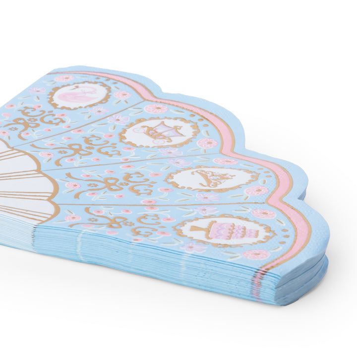 A stack of light blue paper party napkins with a scalloped edge, decorated with pink and gold illustrations of cakes, cupcakes, a carousel, and ornate scrollwork on a white background.