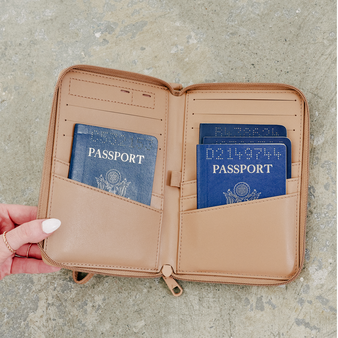 Hand holding the open passport holder with two US passports tucked into the pockets