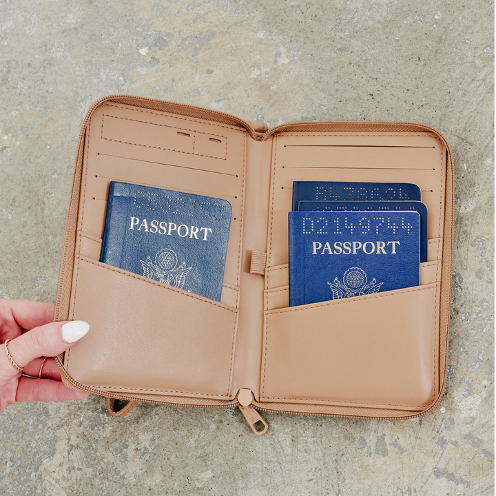 Hand holding the open passport holder with two US passports tucked into the pockets