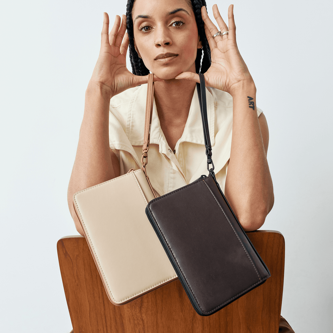 Model with a sand passport holder and a dark brown version worn on a strap