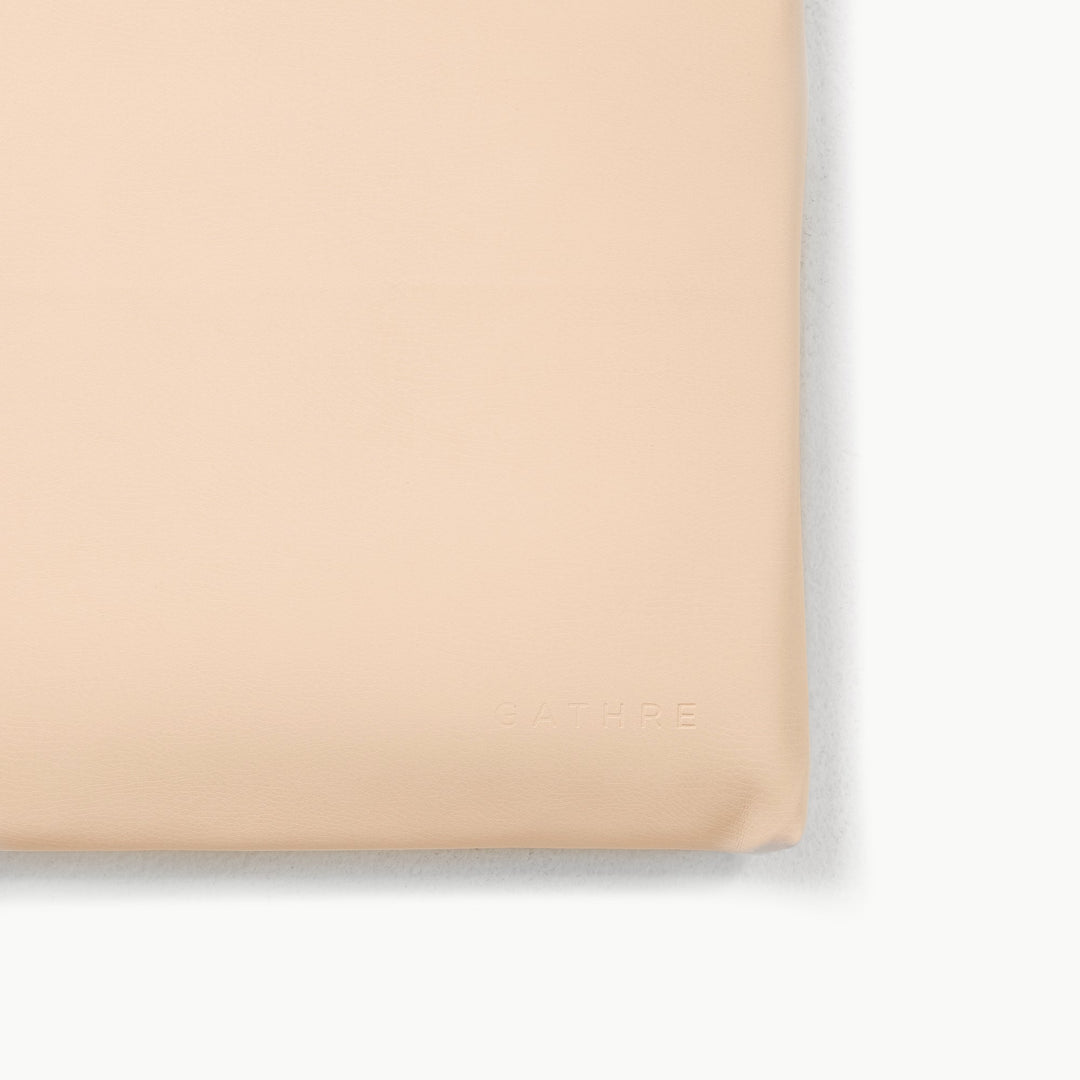Close-up corner of the petal cream vegan leather padded play mat with an embossed logo