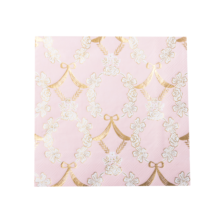 A stack of pink paper napkins featuring a repeating pattern of white cherry blossoms and gold bow motifs, shown on a clean white background.